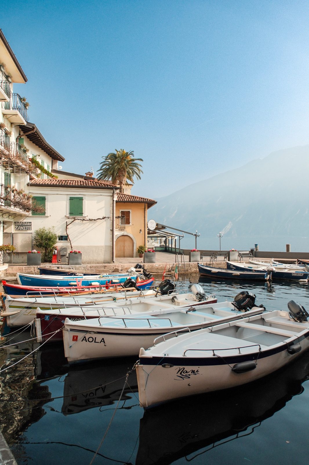 Harbour with wooden boats and a lakeside hotel at Lago di Garda